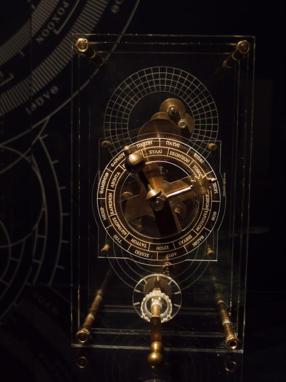 A modern physical reconstruction of the Antikythera Mechanism on display, showing dials and gearwork