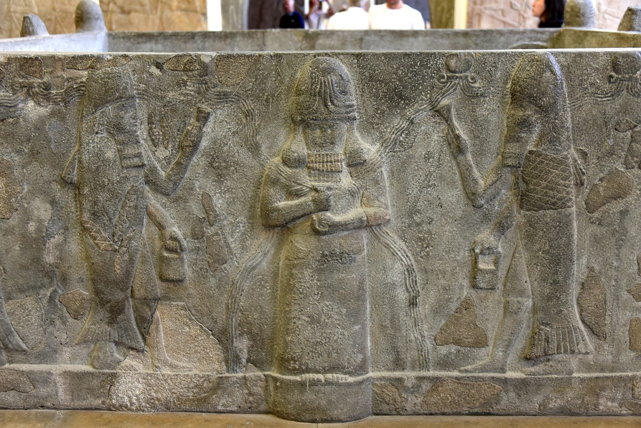 A basalt water basin from Assur showing the god Ea flanked by fish-cloaked apkallu figures