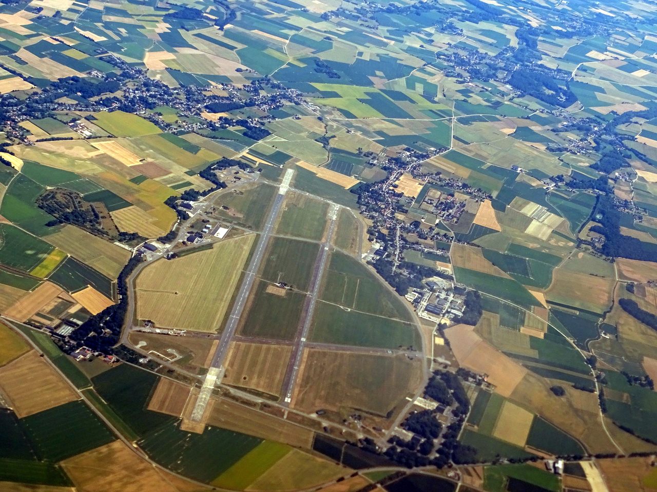 An aerial view of Beauvechain air base in Belgium, its parallel paved strips and taxiways set among farmland and villages