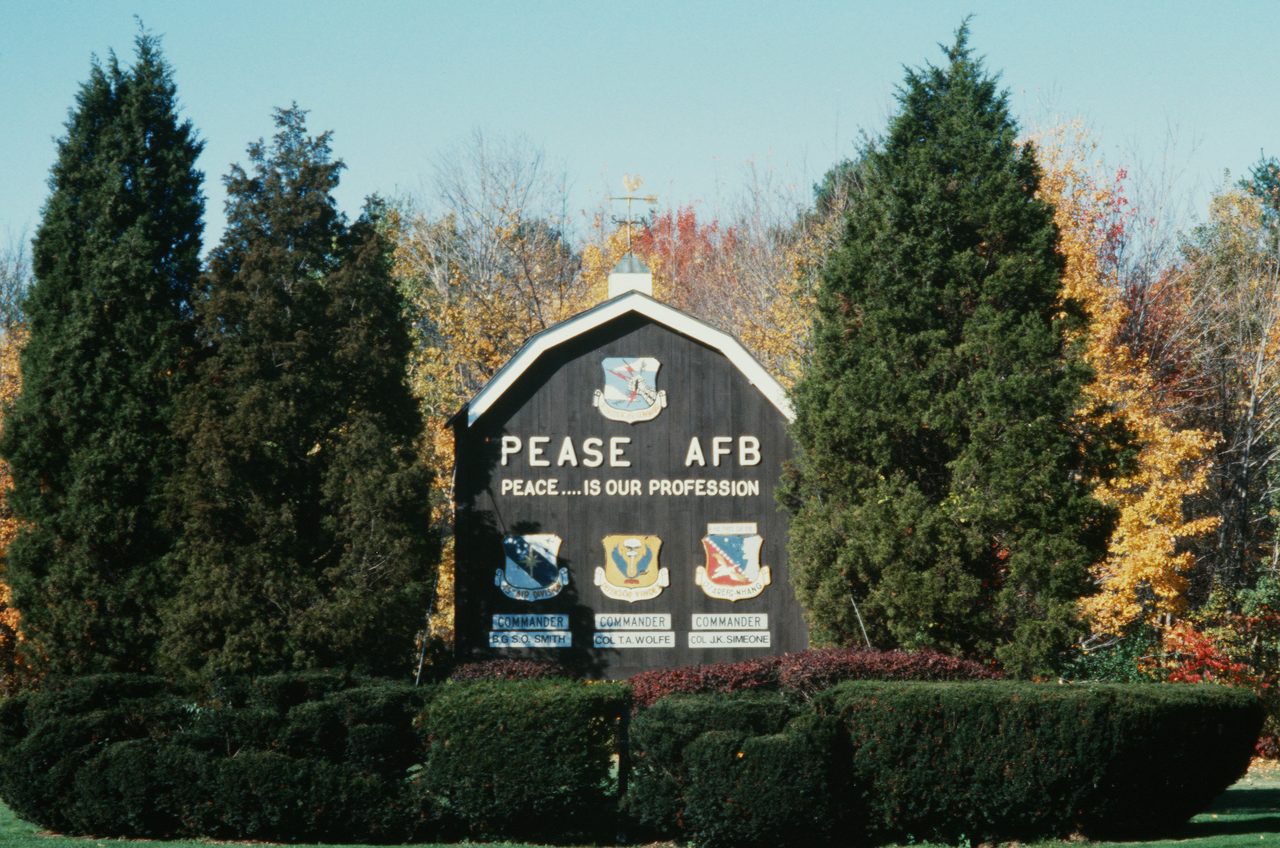 The main entrance sign at Pease Air Force Base, New Hampshire, carrying several Air Force unit shields, photographed in 1987.