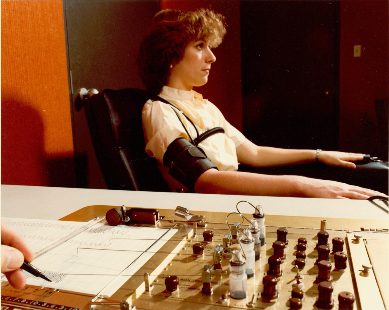 A polygraph examiner making notes on a chart readout while administering a polygraph examination.
