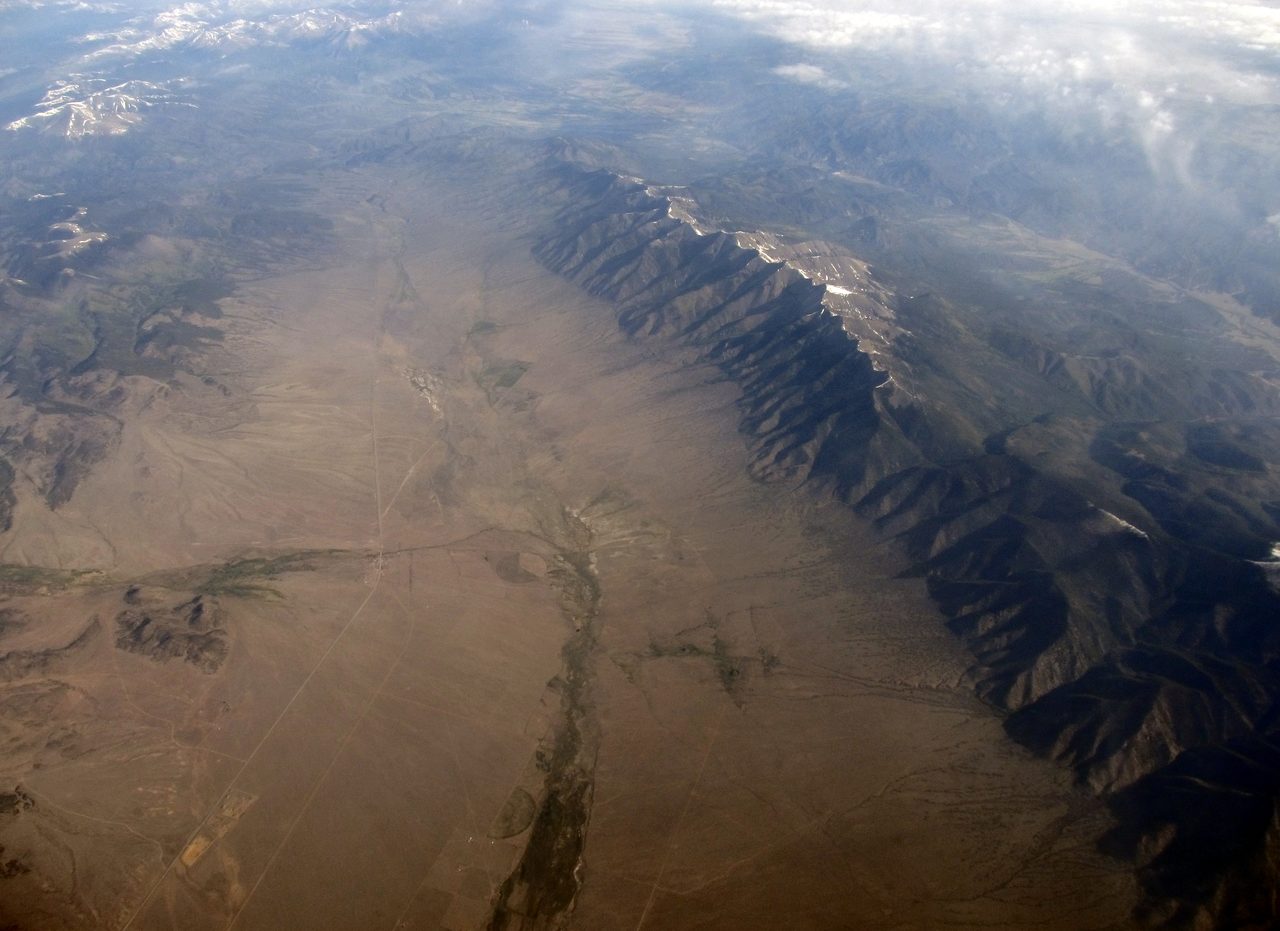 A high aerial view of an arid valley floor in Colorado with a mountain range running across it