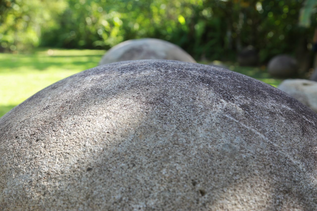 Multiple Diquis stone spheres sitting in a grassy field at the Finca 6 archaeological site, Costa Rica