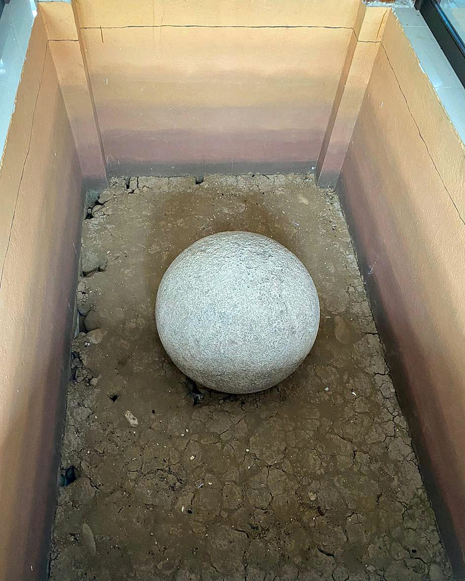 A single Diquis stone sphere on display at the site museum at Finca 6, showing its smooth, worked surface up close