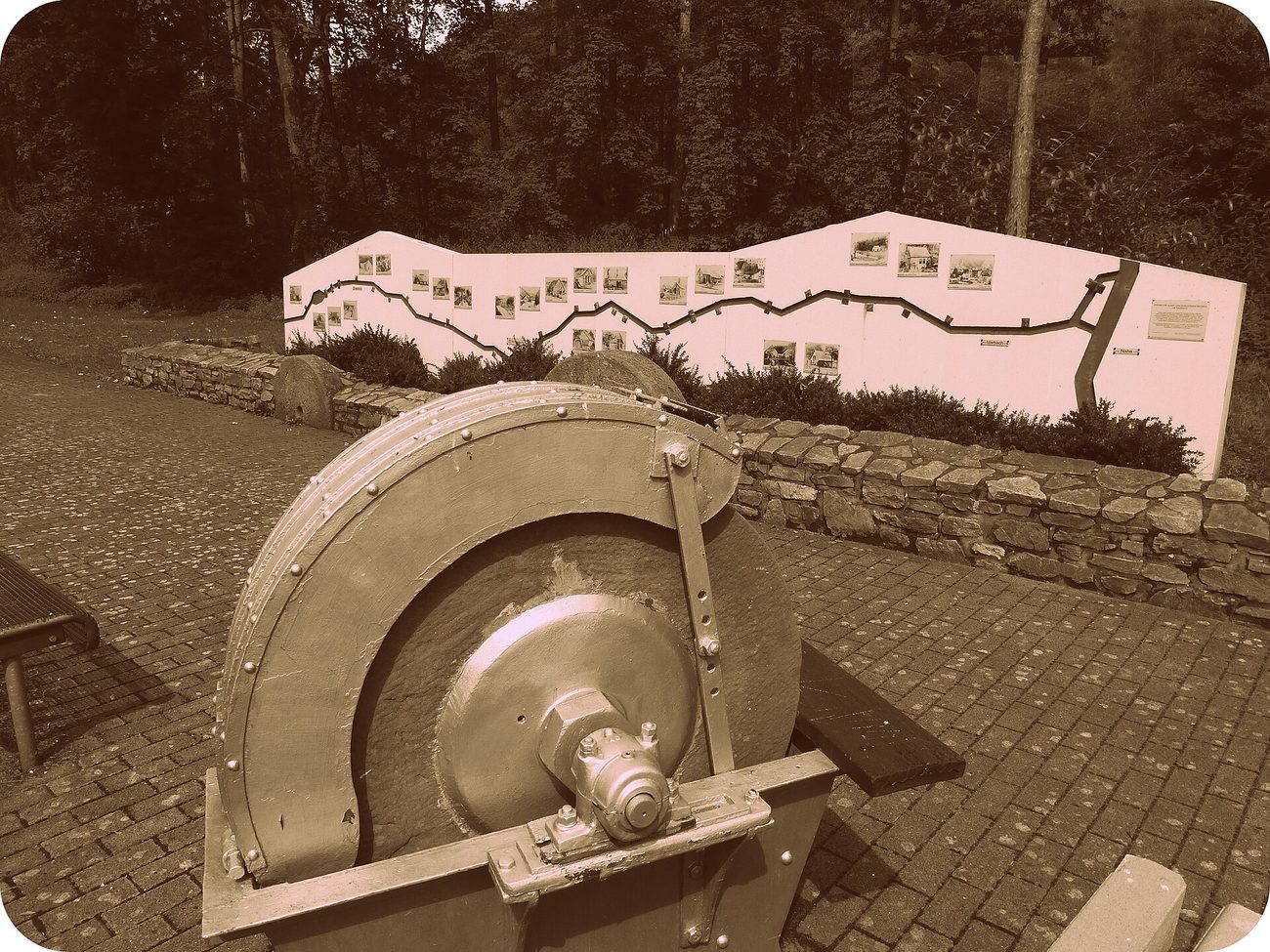 A large historic sandstone grinding wheel on display outdoors at Idar-Oberstein