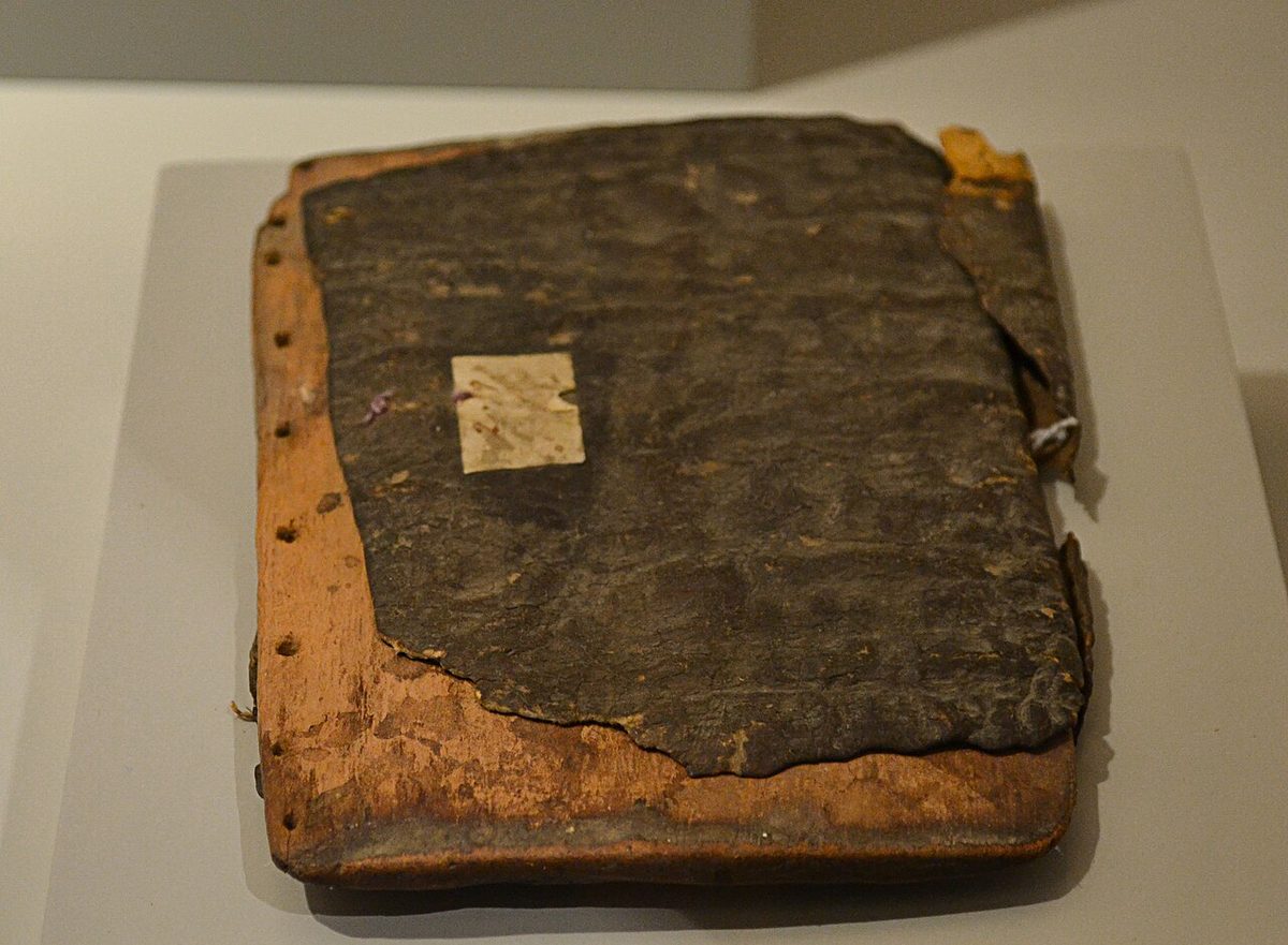 A flat wooden board faced with hide, used to shape an infant's head