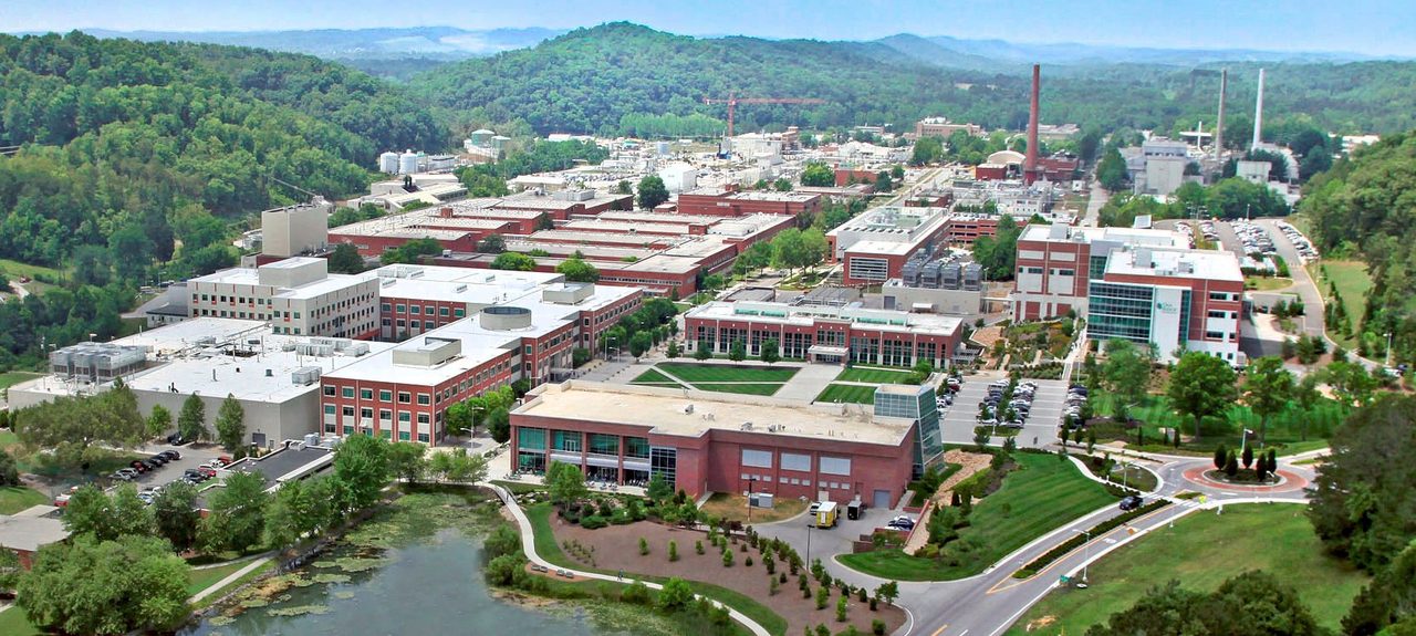 An aerial view of the Oak Ridge National Laboratory campus in Tennessee, showing research buildings set among wooded hills
