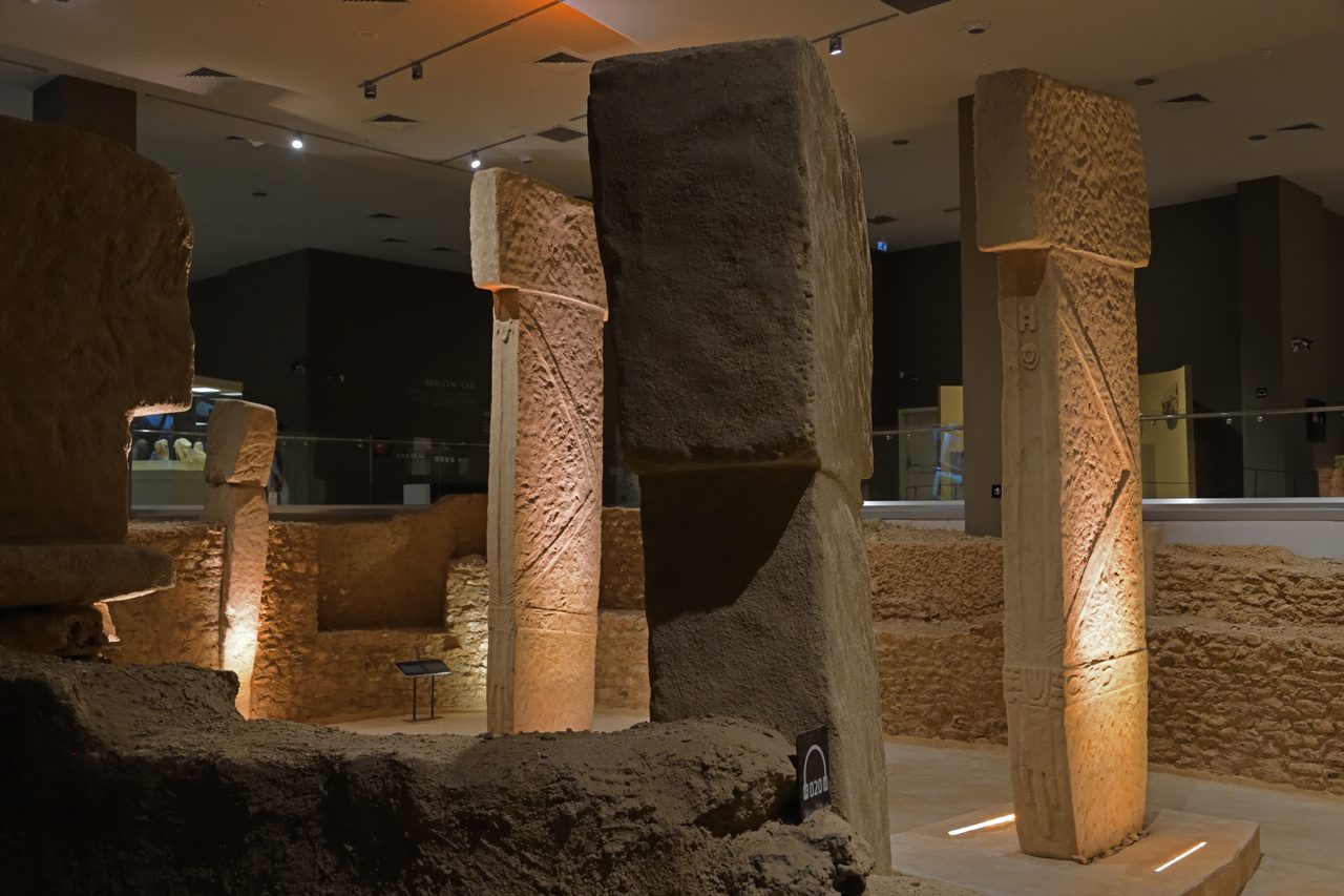 A full-scale museum replica of the two central T-shaped pillars of Enclosure D at Gobekli Tepe, showing carved arms and a belt