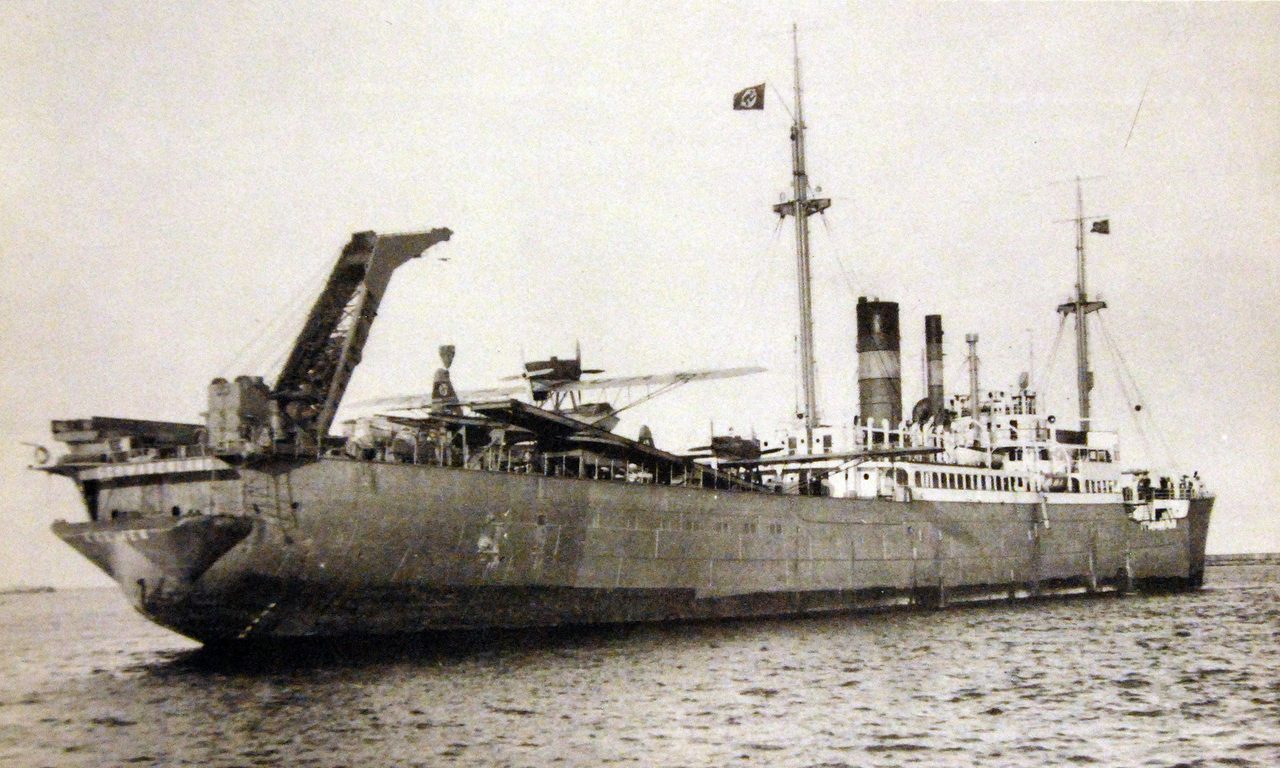 A 1939 photograph of the German catapult seaplane tender MS Schwabenland at sea, seen in near profile with a twin-float seaplane sitting on her deck