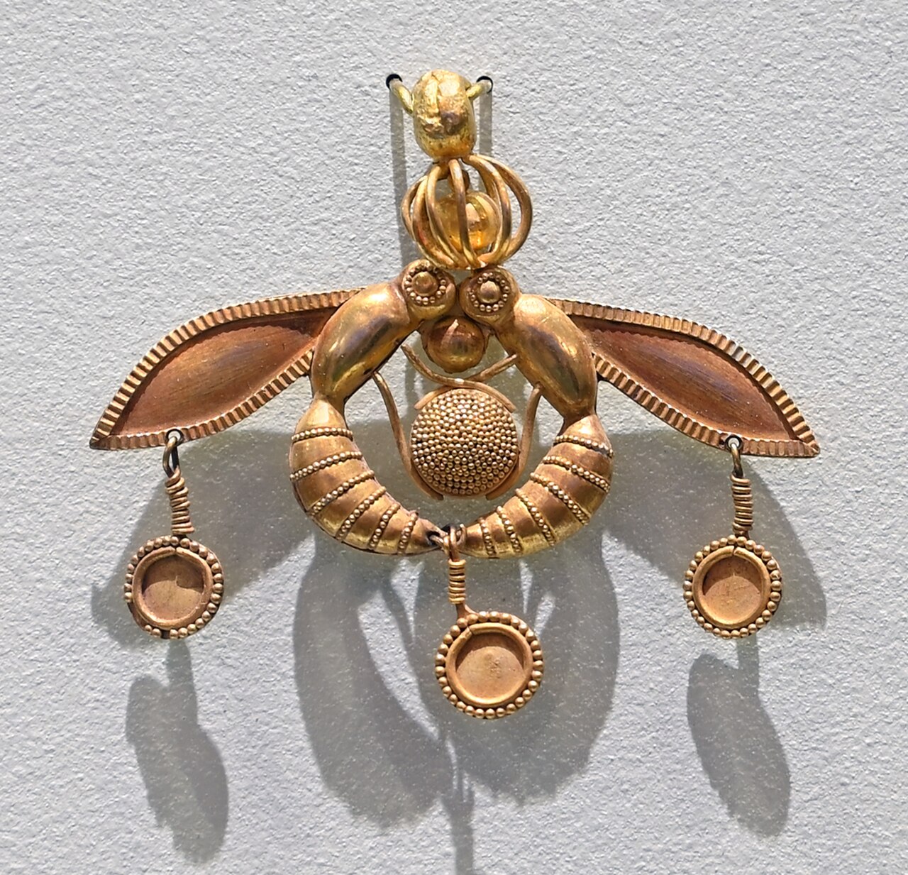 Minoan gold pendant of two bees curved around a honeycomb