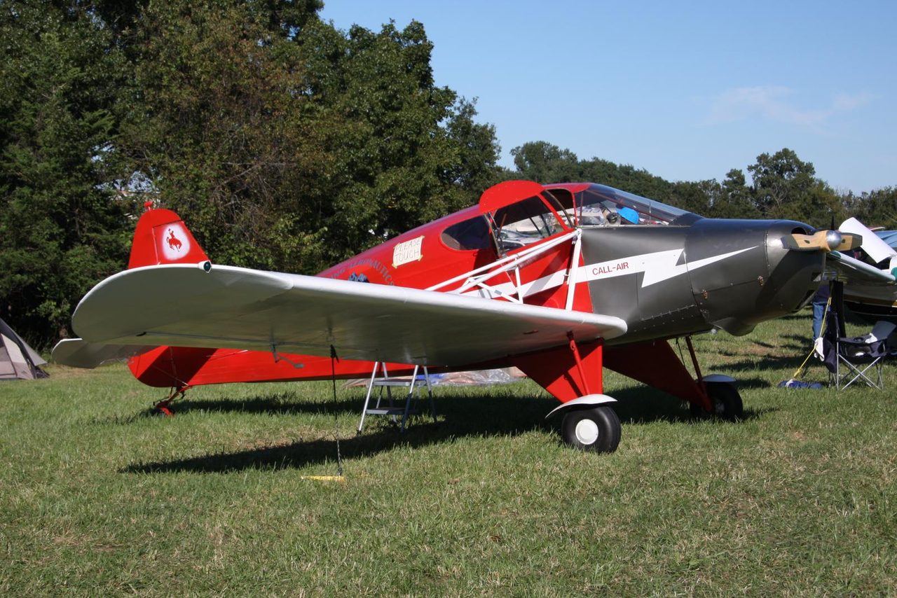 A preserved red and silver CallAir A-2 light aircraft parked on grass at an airfield gathering