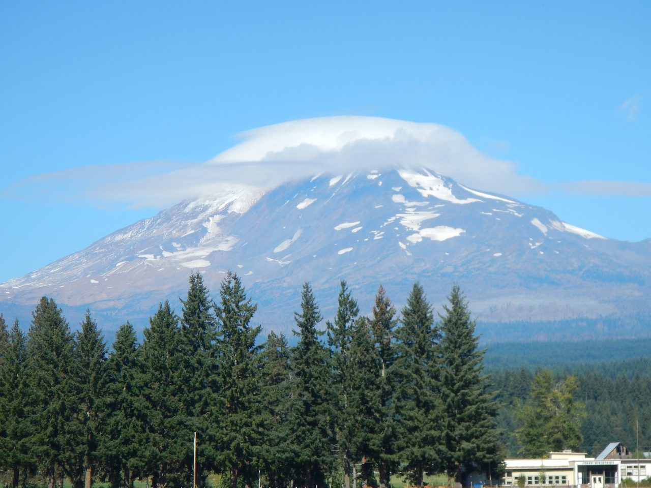 A lens-shaped lenticular cloud capping the summit of Mount Adams under a clear blue sky