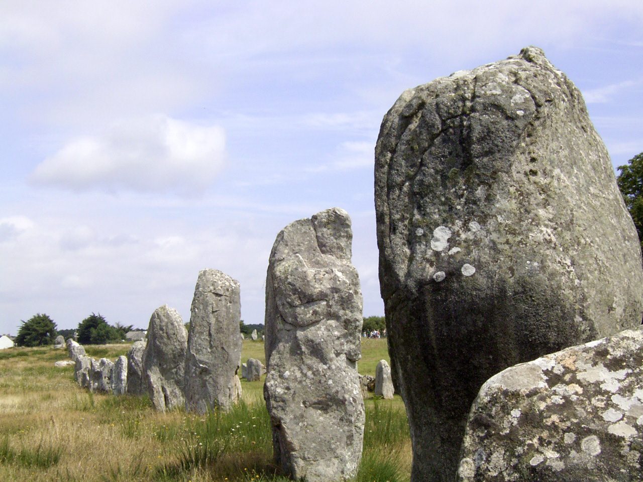 Rows of standing megalithic stones stretching across open ground at the Menec alignments near Carnac, Brittany
