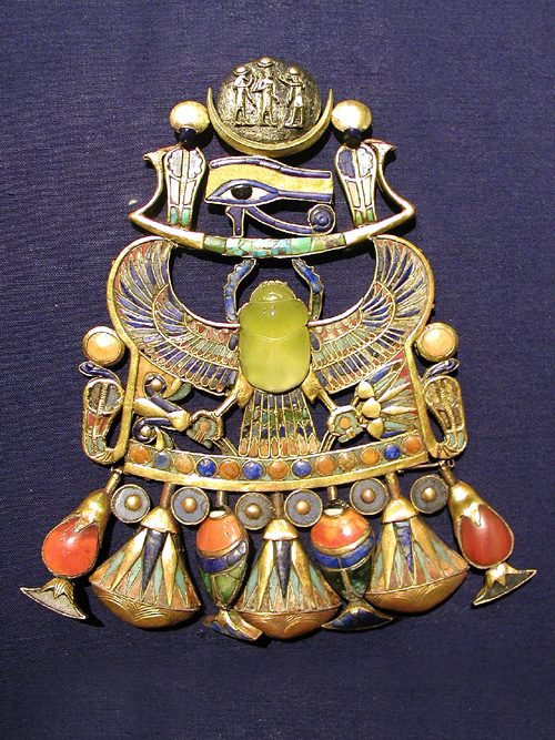A pectoral from Tutankhamun's tomb, a broad gold collar inlaid with colored glass and stones, its central scarab carved from Libyan Desert Glass.
