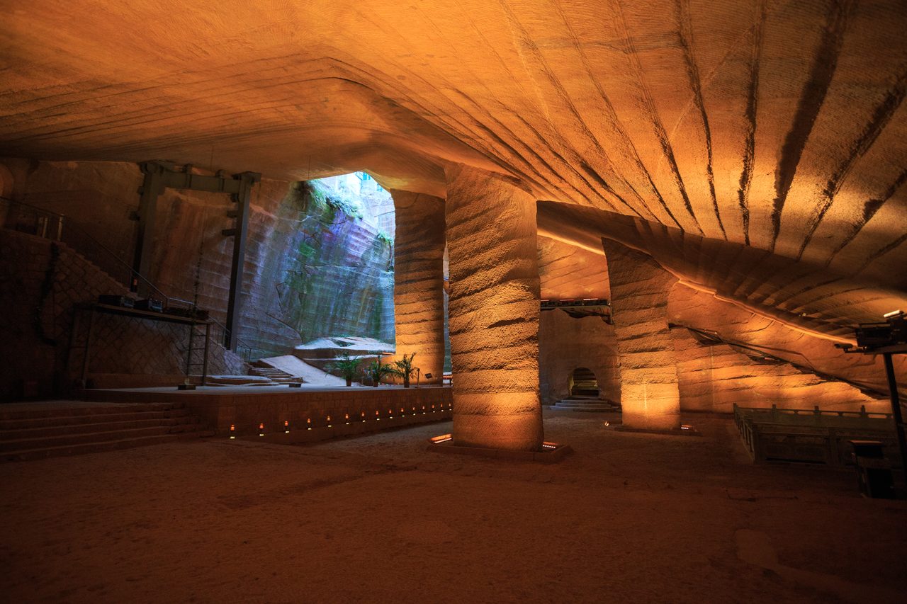 Load-bearing carved stone pillars left standing inside a wide chamber at the Longyou Caves, with chisel marks visible on the ceiling and walls