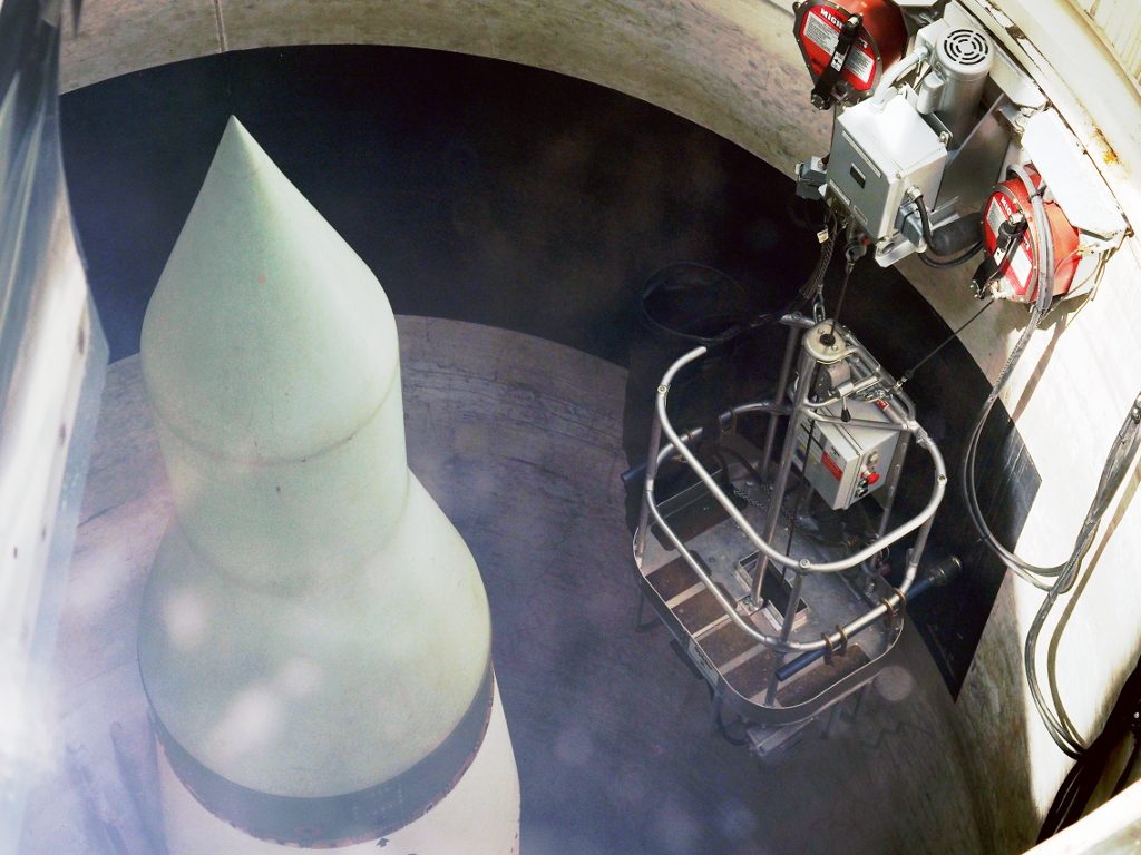Looking down into a preserved Minuteman silo at the missile's nose cone, with a work platform and junction boxes beside it