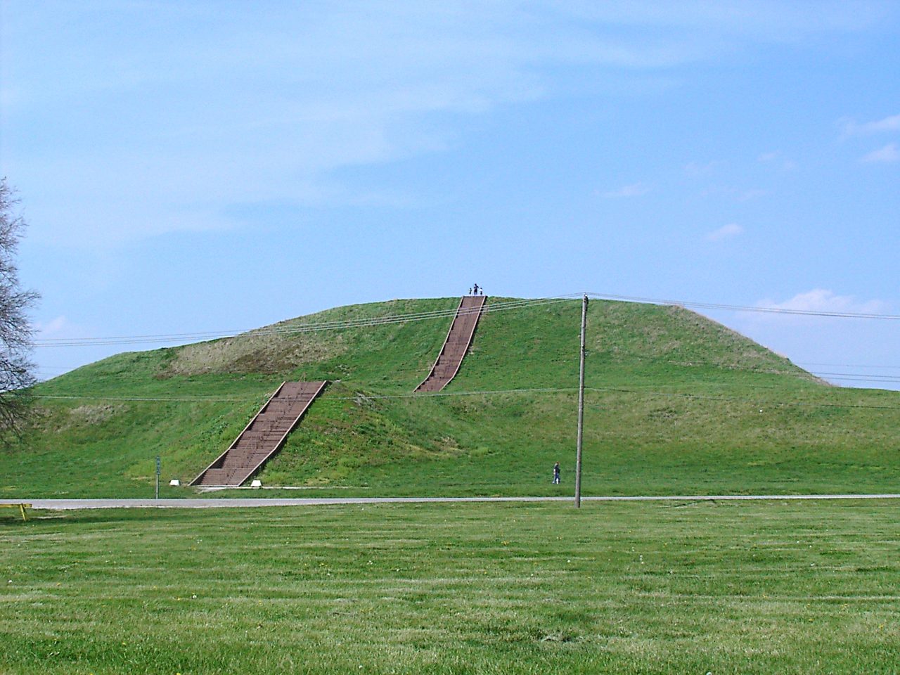 Monks Mound at the Cahokia site near Collinsville, Illinois, a broad grass-covered earthwork with a modern staircase running up its front