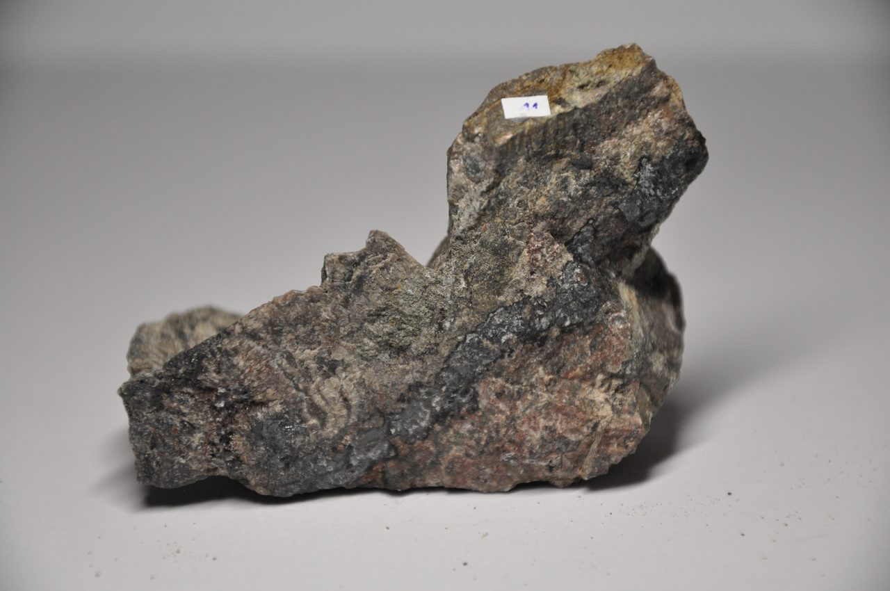 A dark, dense specimen of uraninite, the black uranium oxide ore mineral, with a metallic luster.