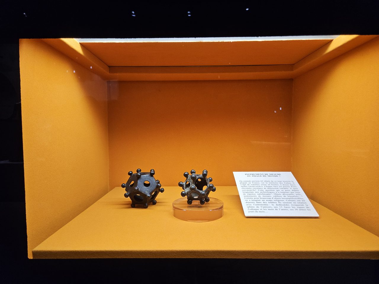 A hollow bronze Roman dodecahedron with circular holes of different sizes on each face and a knob at every corner