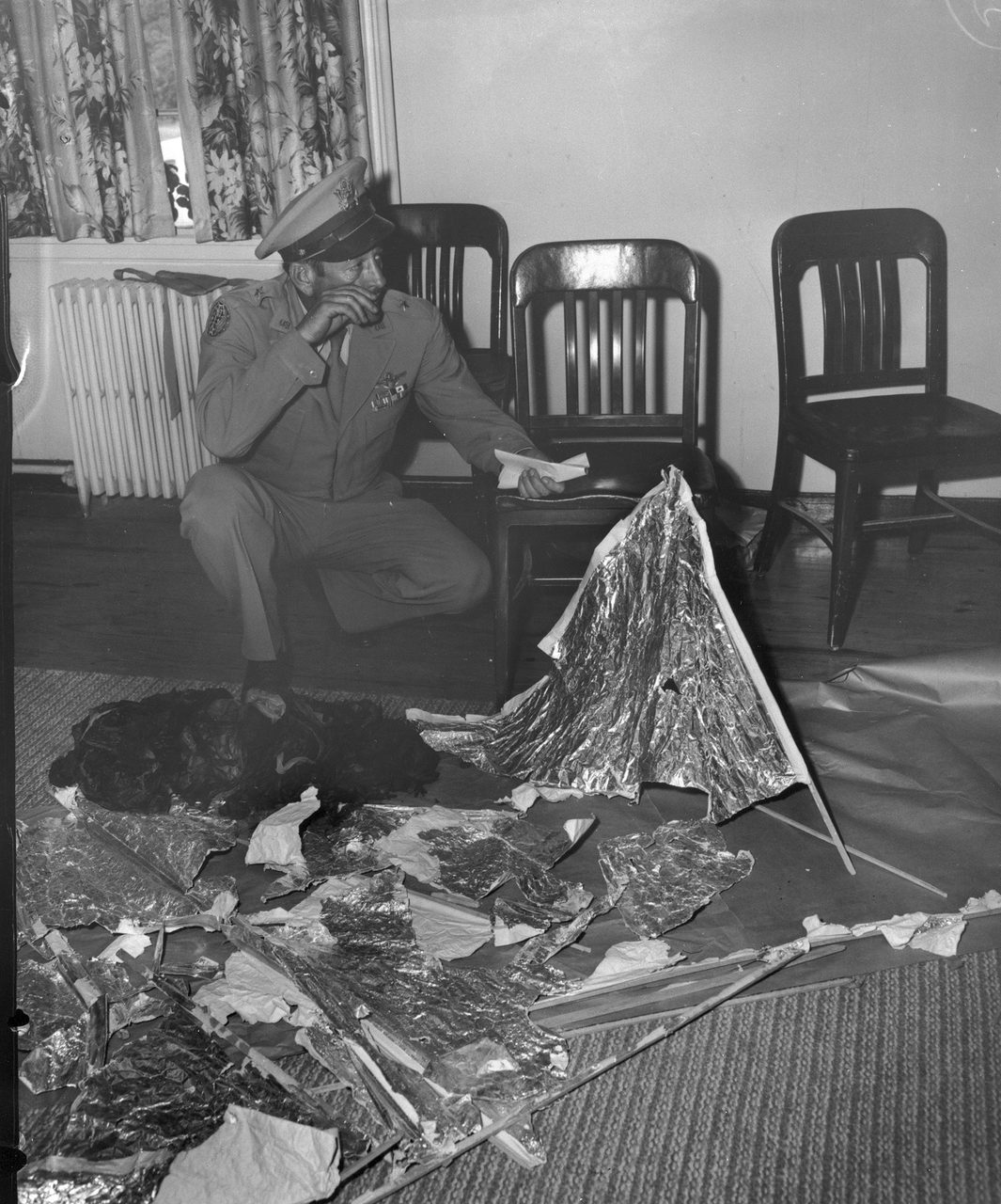 Brigadier General Roger Ramey inspecting debris from the Roswell incident at Fort Worth Army Air Field, July 8, 1947, a sheet of paper in his hand