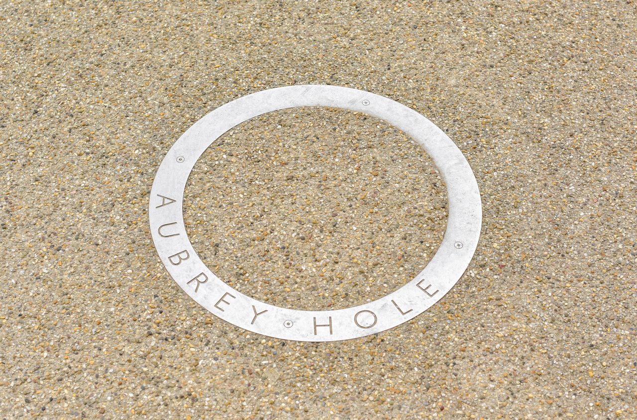 A modern ground-level marker at Stonehenge showing the position of one of the 56 Aubrey Holes from the monument's first construction phase