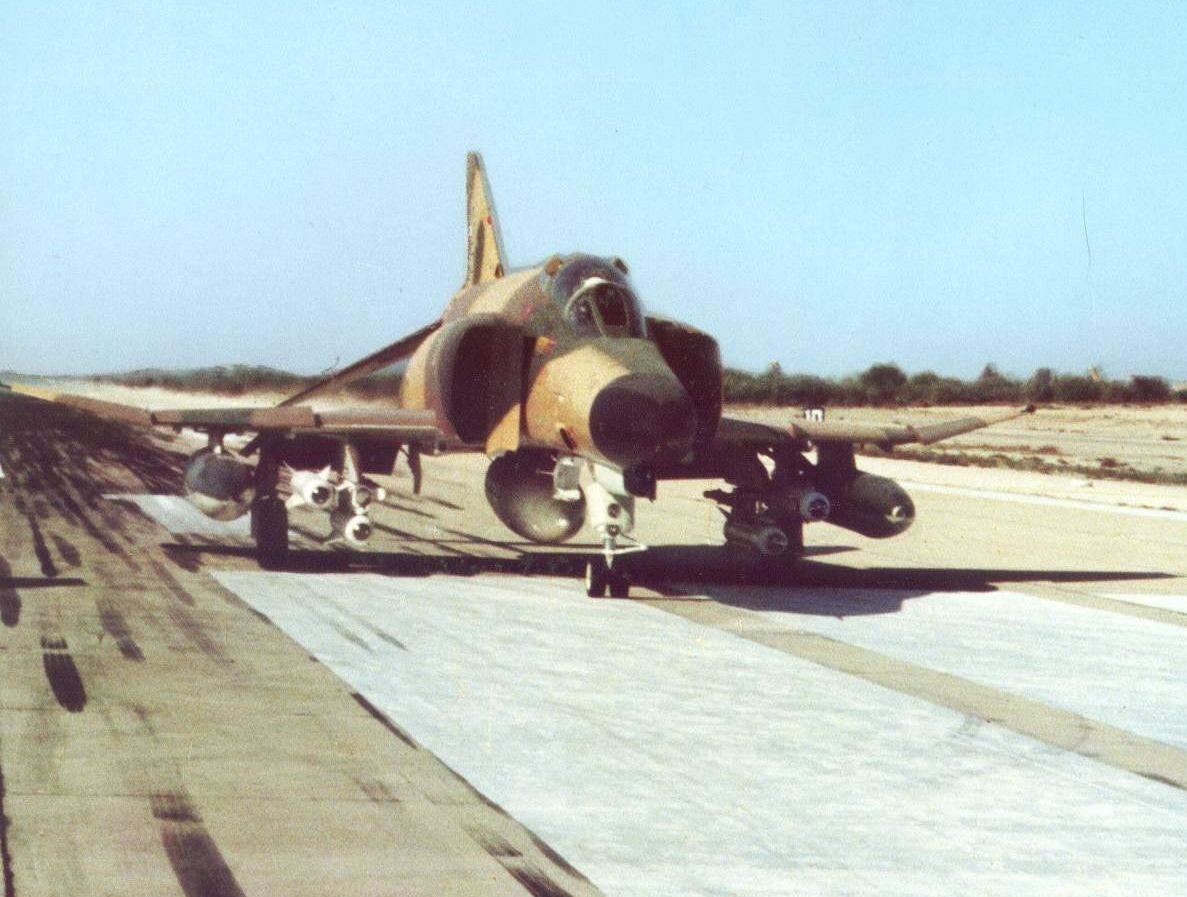 An Imperial Iranian Air Force F-4E Phantom II fighter jet armed with missiles, parked on an airbase runway