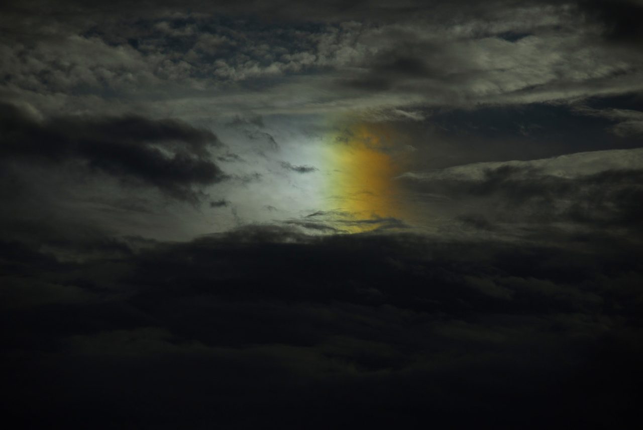A photograph of a parhelion, a bright colored patch of light beside the sun caused by sunlight refracting through ice crystals.