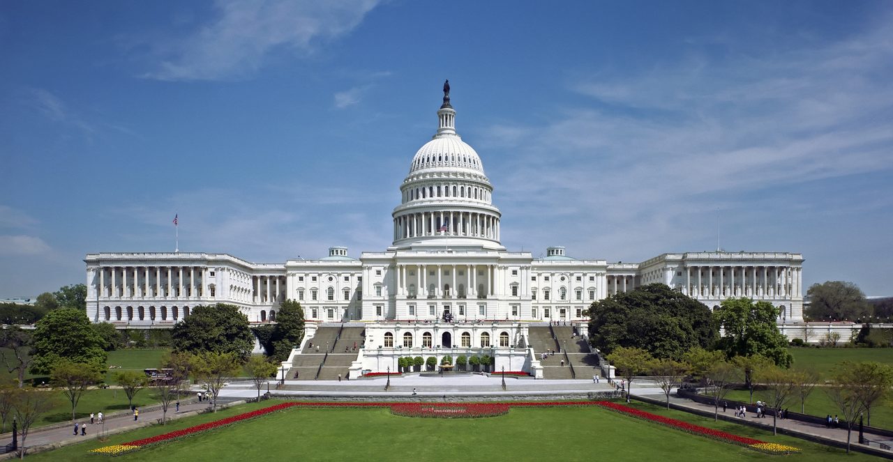 The west front of the United States Capitol building under a clear blue sky, its white dome topped by the Statue of Freedom