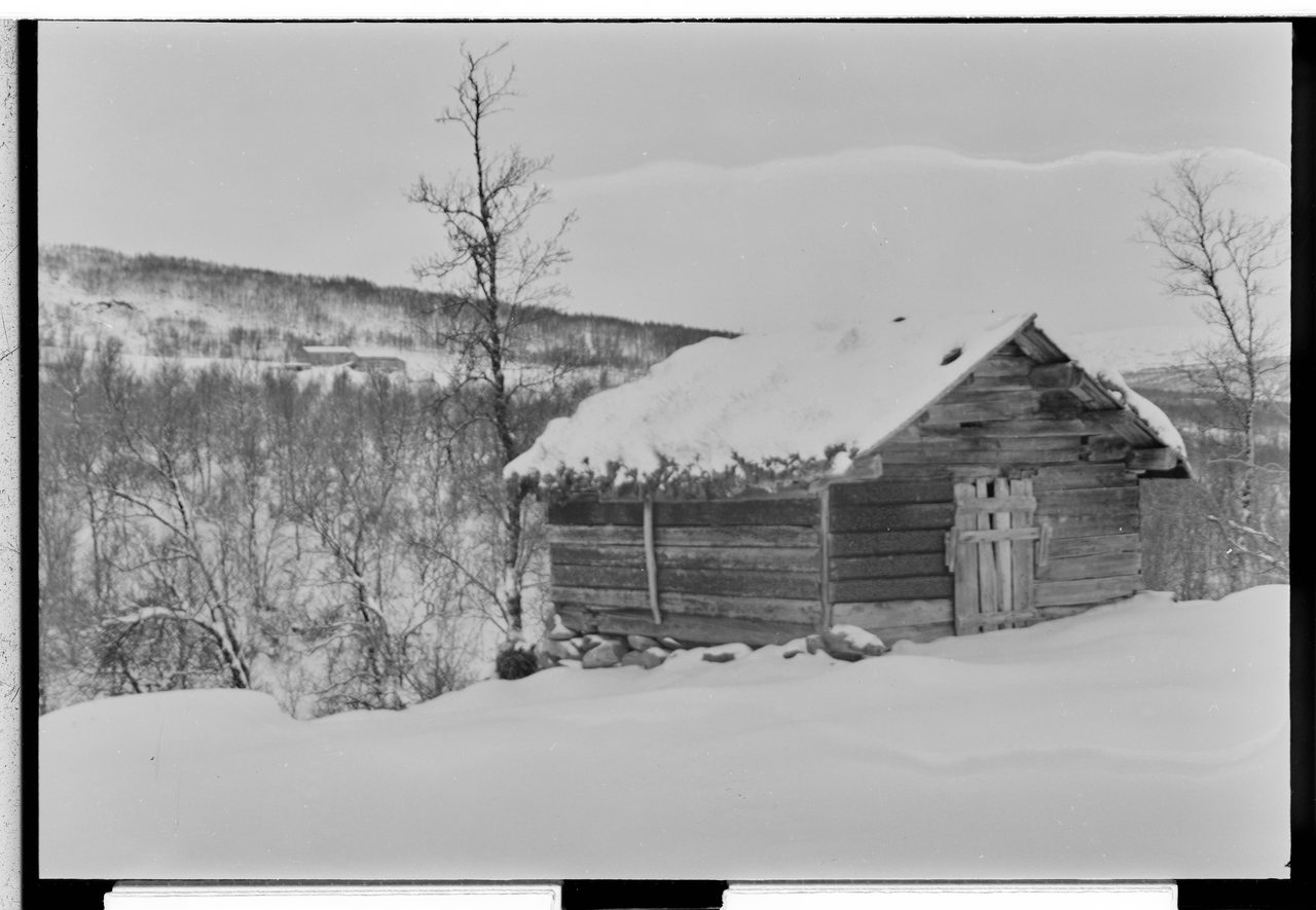 A 1953 black-and-white winter photograph of the Hessdalen hamlet in Norway, showing farmhouses in a snow-covered valley