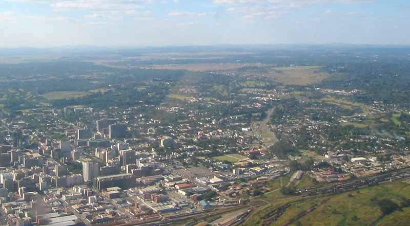 An aerial view of Harare, Zimbabwe, showing a built-up city centre, suburbs and rail yards